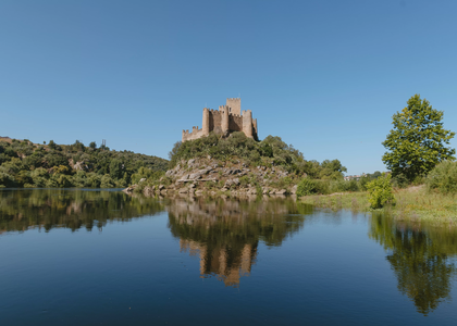 View of Almourol Castle on a small island in the Tagus River, surrounded by nature and reflected in the calm water