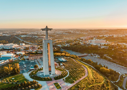 Drone shot of the Cristo Rei statue in Almada overlooking Lisbon during sunset