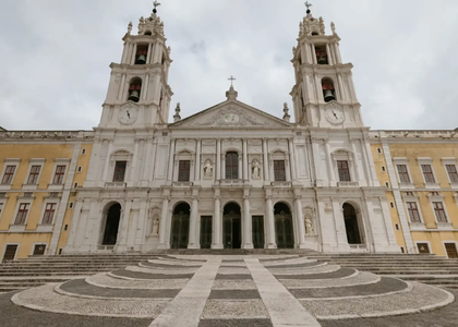 Front view of the Mafra National Palace with twin bell towers and patterned stone steps, Portugal.