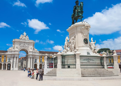 View of Praça do Comércio in Lisbon, Portugal, with the Arco da Rua Augusta and the statue of King José I under a bright blue sky.