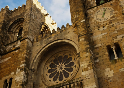 Close-up view of the façade of Lisbon Cathedral (Sé de Lisboa) in Portugal, showcasing its rose window and clock tower.