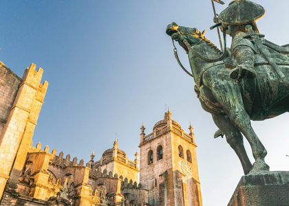 View of Porto Cathedral and the statue of Vímara Peres bathed in golden evening light.