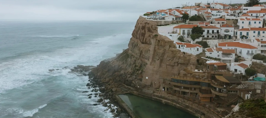 Azenhas do Mar, a cliffside village in Portugal with white houses, red rooftops, and a natural ocean pool by the Atlantic coast.