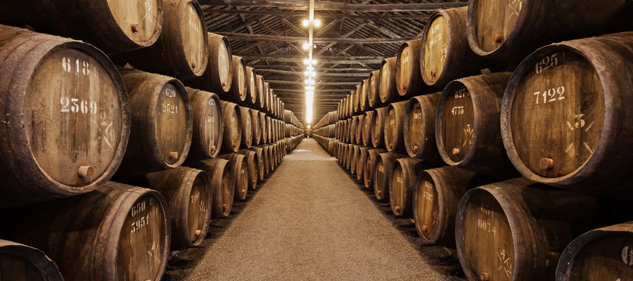 Traditional Port wine cellars in Vila Nova de Gaia, Portugal, with rows of oak barrels aging wine.
