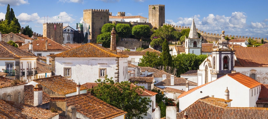 Panoramic view of Óbidos historic center with whitewashed houses, red-tiled roofs, and the medieval castle in the background, Portugal.