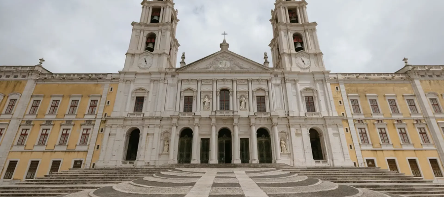 Front view of the Mafra National Palace with twin bell towers and patterned stone steps, Portugal.