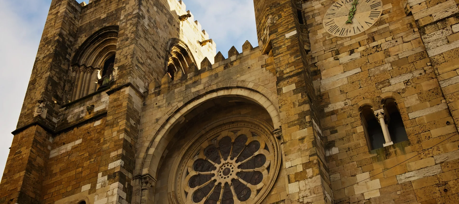 Close-up view of the façade of Lisbon Cathedral (Sé de Lisboa) in Portugal, showcasing its rose window and clock tower.
