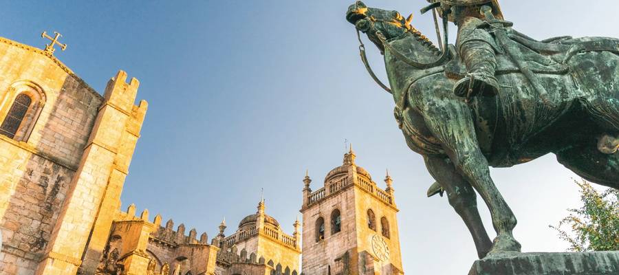View of Porto Cathedral and the statue of Vímara Peres bathed in golden evening light.
