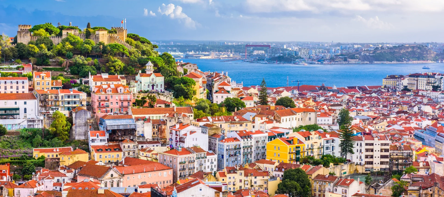 Panoramic view of Lisbon with São Jorge Castle, colorful houses, and the Tagus River in the background.