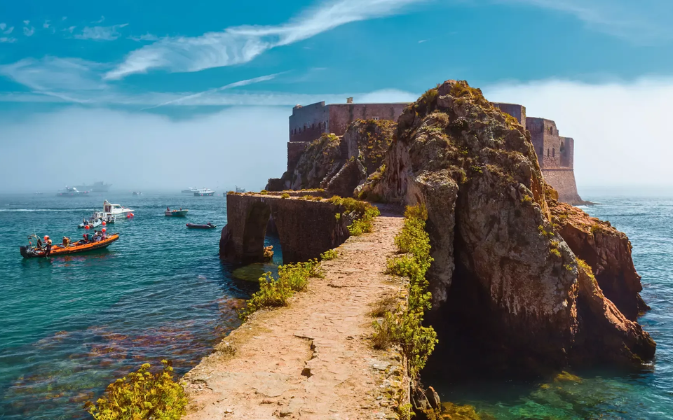 Stone path leading to the Fortress of São João Baptista on Berlenga Island, surrounded by turquoise Atlantic waters and boats.