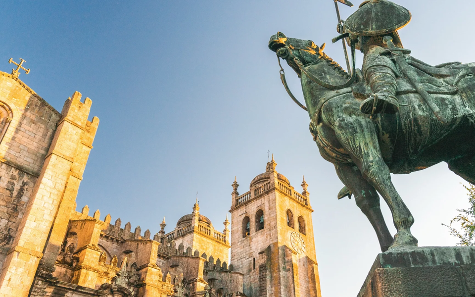 View of Porto Cathedral and the statue of Vímara Peres bathed in golden evening light.