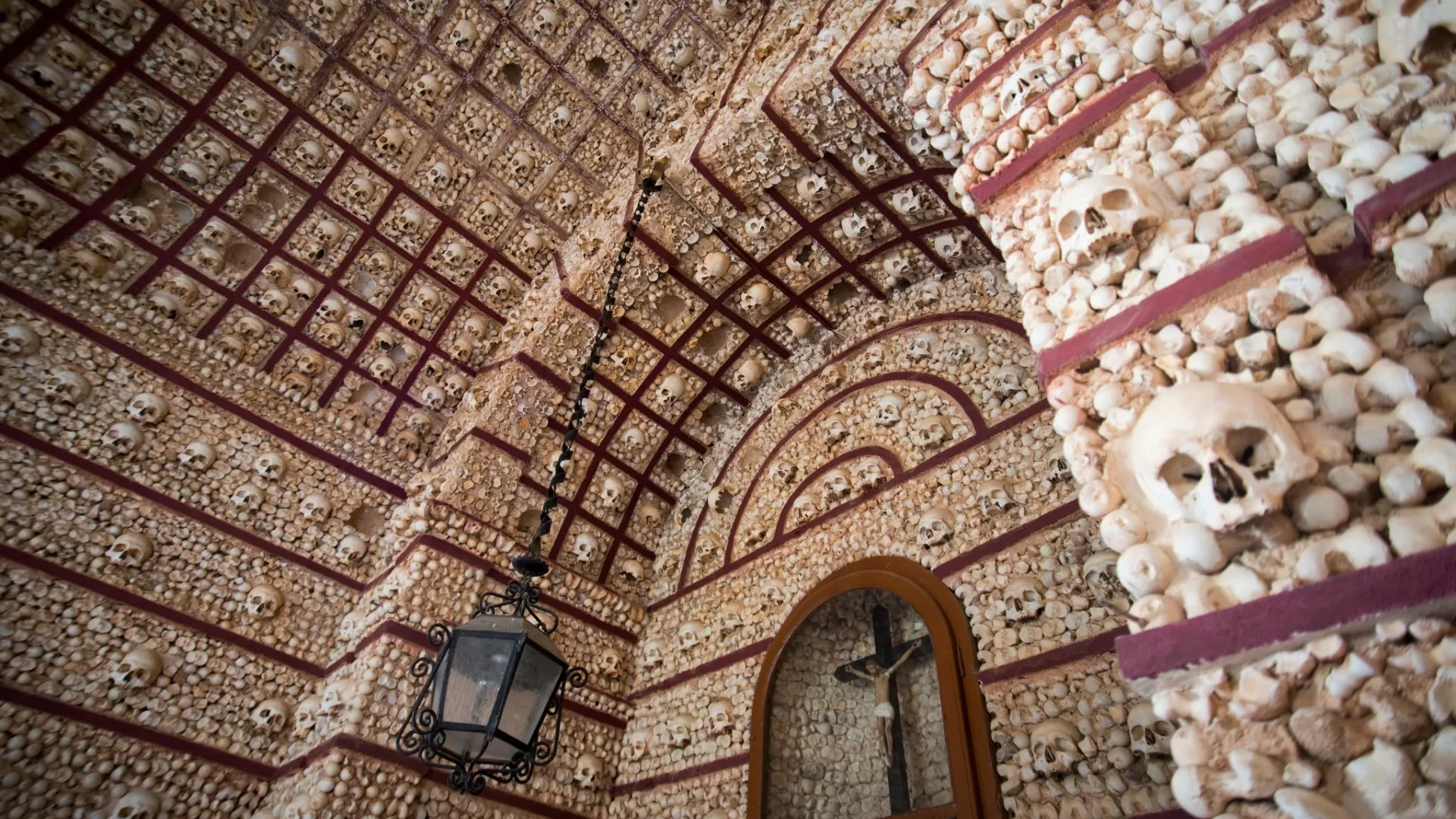 Interior view of the Chapel of Bones in Évora, Portugal, with walls and ceiling decorated with human skulls and bones.