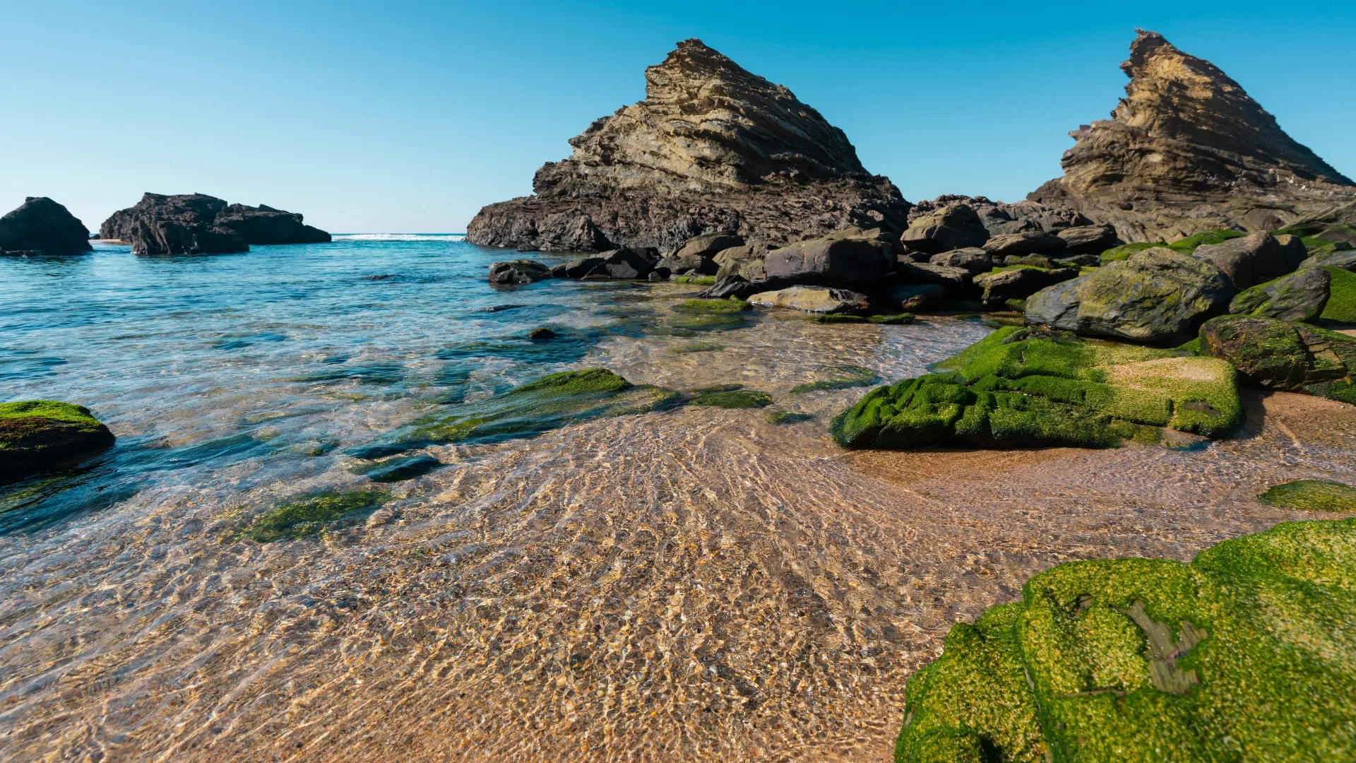 Scenic view of Praia da Samoqueira beach in Portugal, with golden sand, rock formations, and turquoise waters