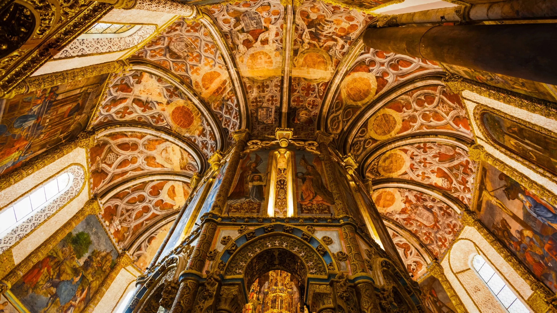 Interior view of the Charola, the Templar rotunda at the Convent of Christ in Tomar, with painted vaults and intricate gold detailing.