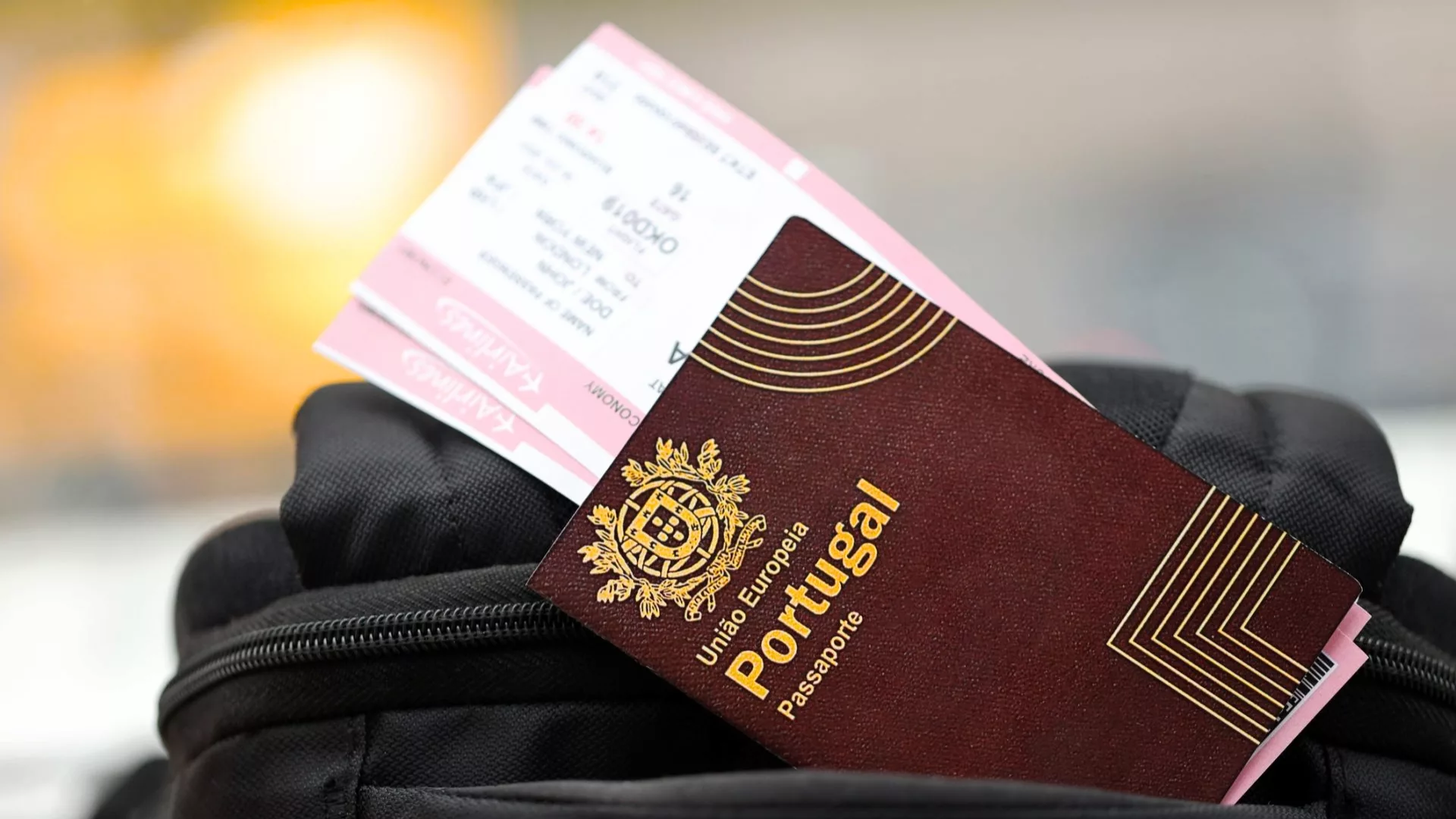 Portuguese passport and train ticket sticking out of a black backpack, ready for travel.