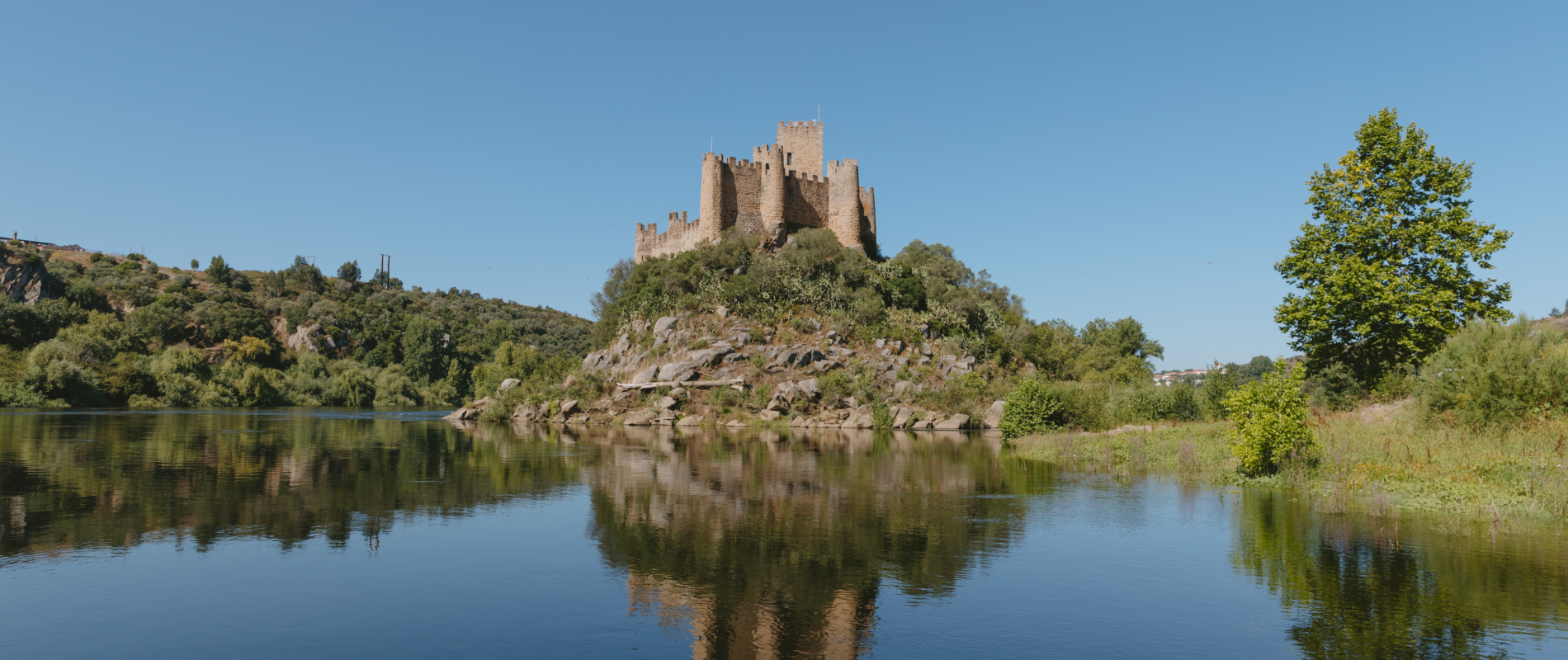 View of Almourol Castle on a small island in the Tagus River, surrounded by nature and reflected in the calm water
