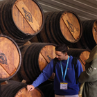 Wine guide explaining ageing barrels to visitors during a cellar tour in a Port wine lodge.