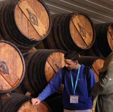 Wine guide explaining ageing barrels to visitors during a cellar tour in a Port wine lodge.