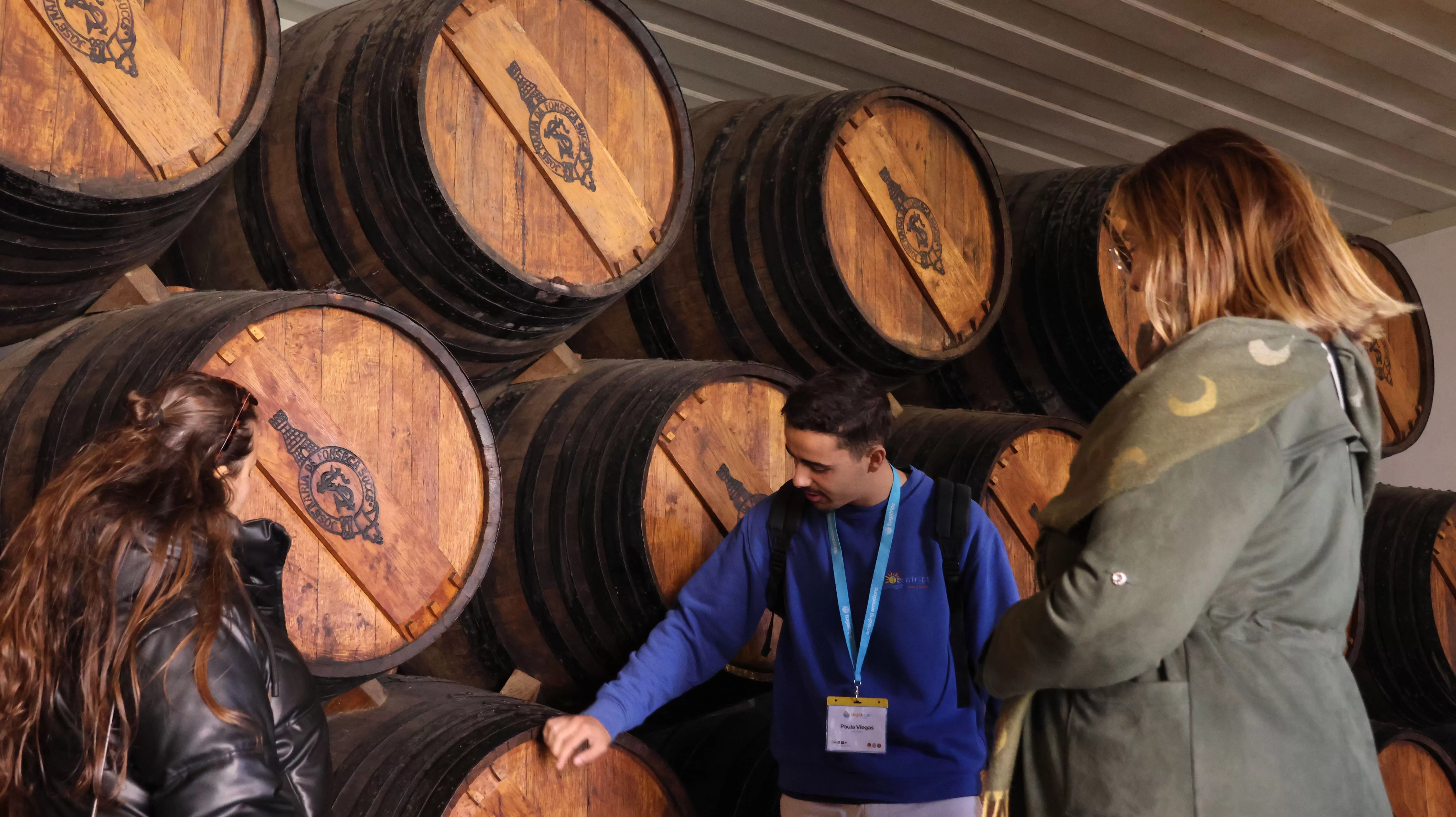 Wine guide explaining ageing barrels to visitors during a cellar tour in a Port wine lodge.