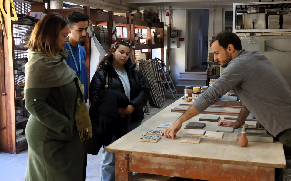Group observing artisan demonstrating traditional tile-making techniques at a workshop