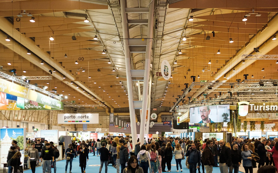 Crowds walking through exhibition booths at Bolsa de Turismo de Lisboa (BTL), showcasing various Portuguese tourism regions