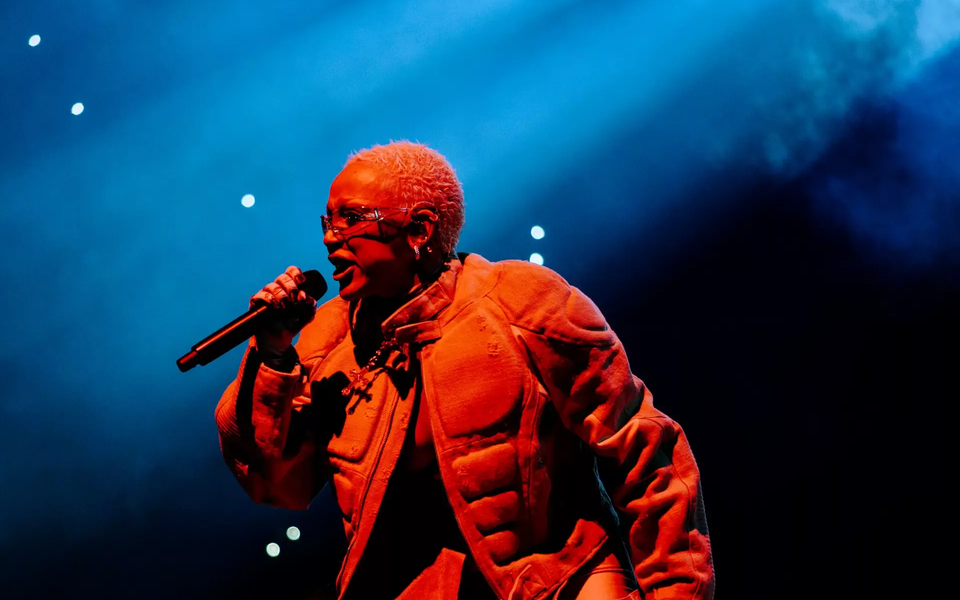 Doja Cat singing passionately into a microphone under dramatic blue lighting during a live performance at Rock in Rio Lisboa 202