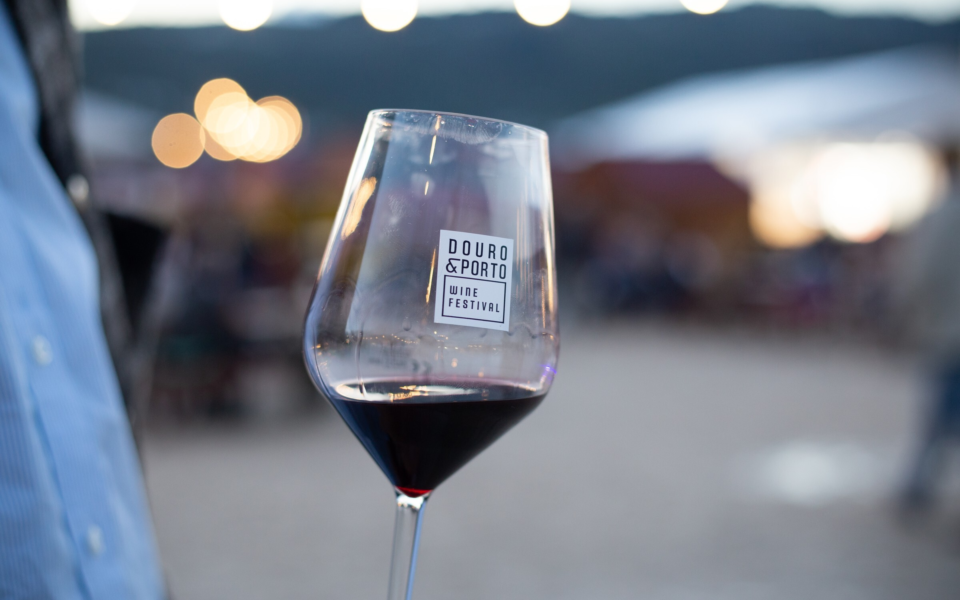Red wine glass featuring the Douro & Porto Wine Festival logo with blurred background lights