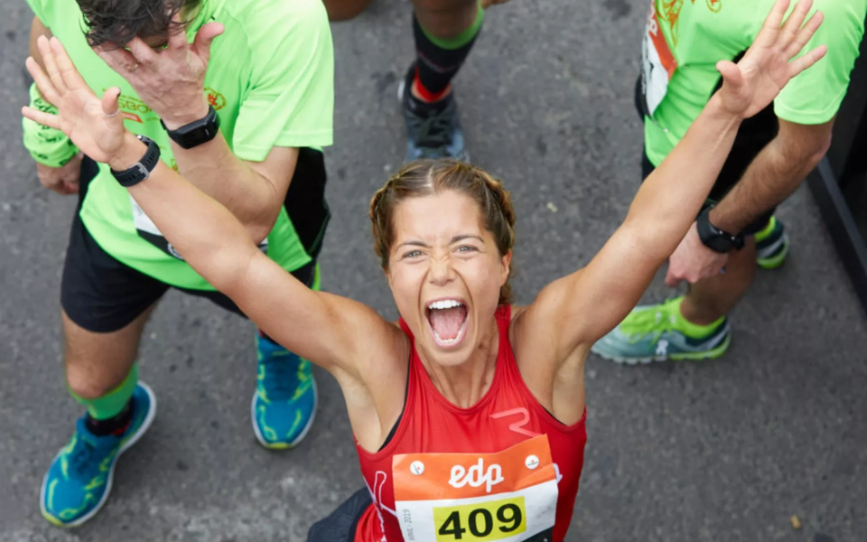 Female runner celebrating with arms raised after finishing the EDP Lisbon Half Marathon