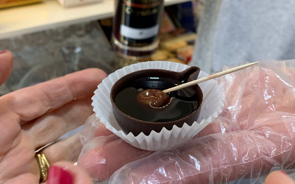 Hand holding a chocolate cup with Ginjinha liqueur and cherry on a toothpick