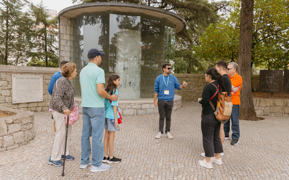 Tour guide with visitors by the Berlin Wall Memorial in Fátima Sanctuary