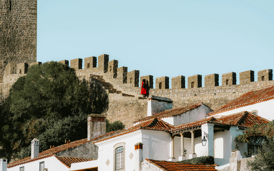 Visitor walking along the medieval walls of Óbidos overlooking the village