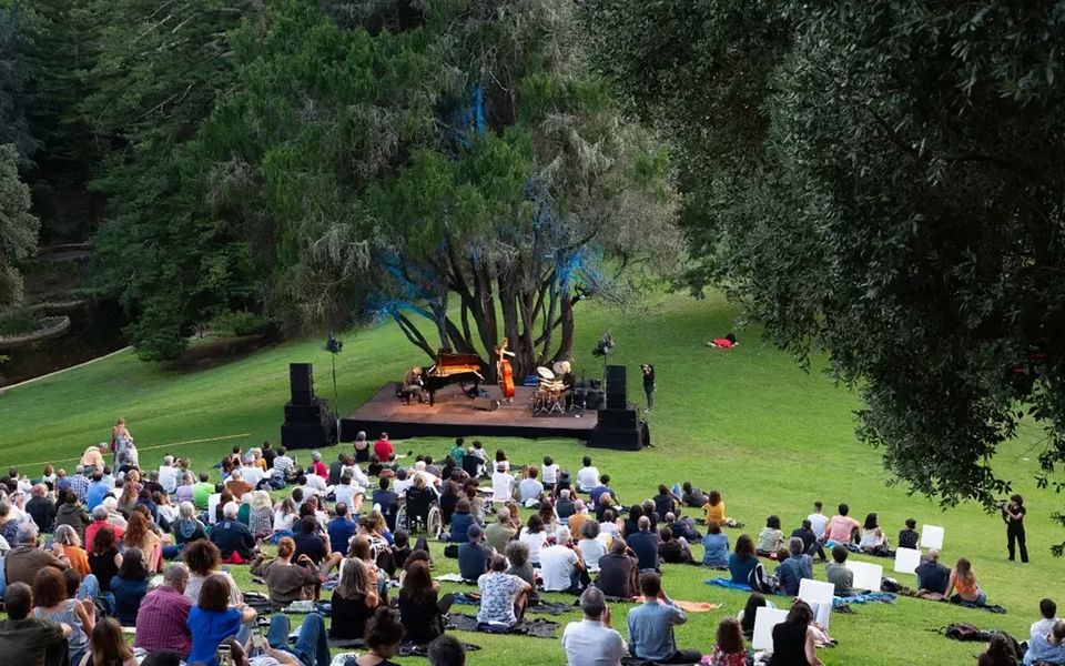 Open-air jazz concert in Monserrate Park, Sintra, with audience seated on the grass enjoying live music under the trees.