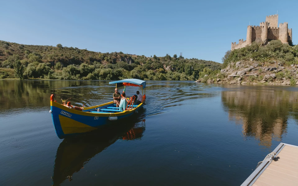 Traditional boat sailing on the Tagus River with Almourol Castle in the background, Portugal.