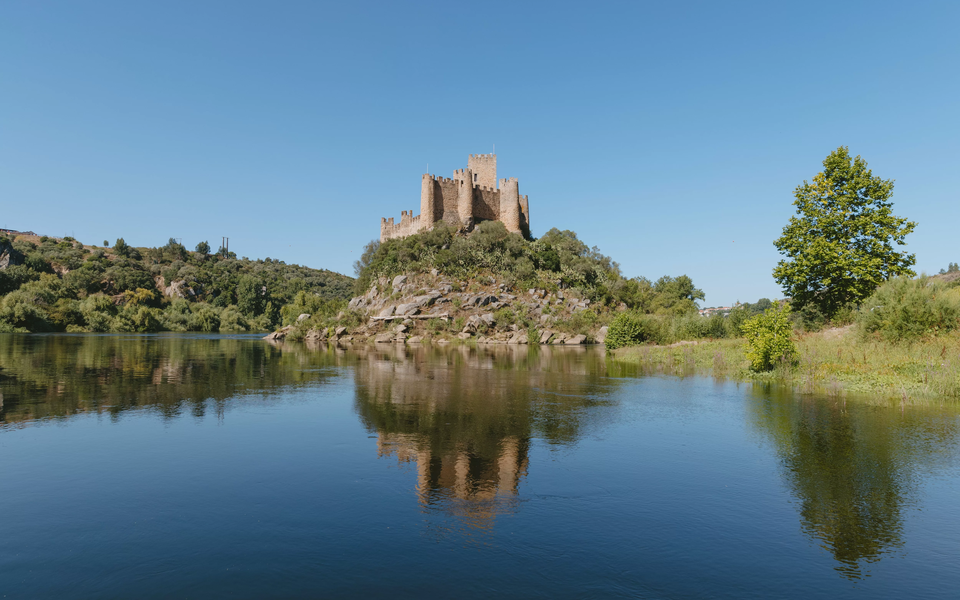 Castle of Almourol reflected in the Tagus River on a clear summer day in Portugal.