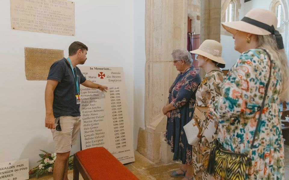 Guide explaining the Pantheon of the Templar Masters inside the Church of Santa Maria do Olival in Tomar, Portugal.