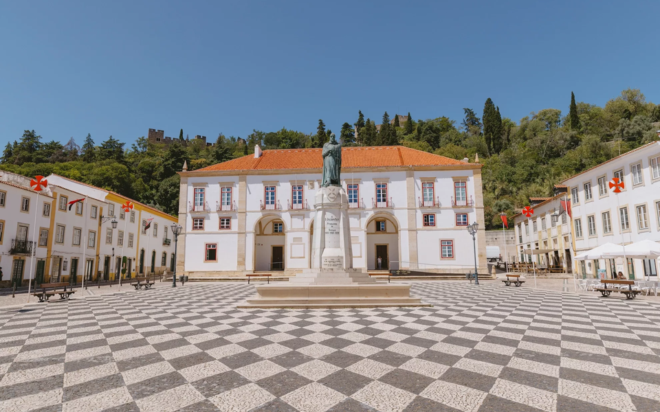 Republic Square in Tomar, Portugal, featuring the statue of Gualdim Pais, founder of the city, with the Templar Castle in the background.