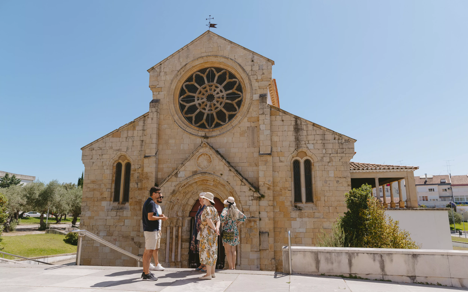 Tour group visiting the Church of Santa Maria do Olivais in Tomar, Portugal, with a guide explaining its history.