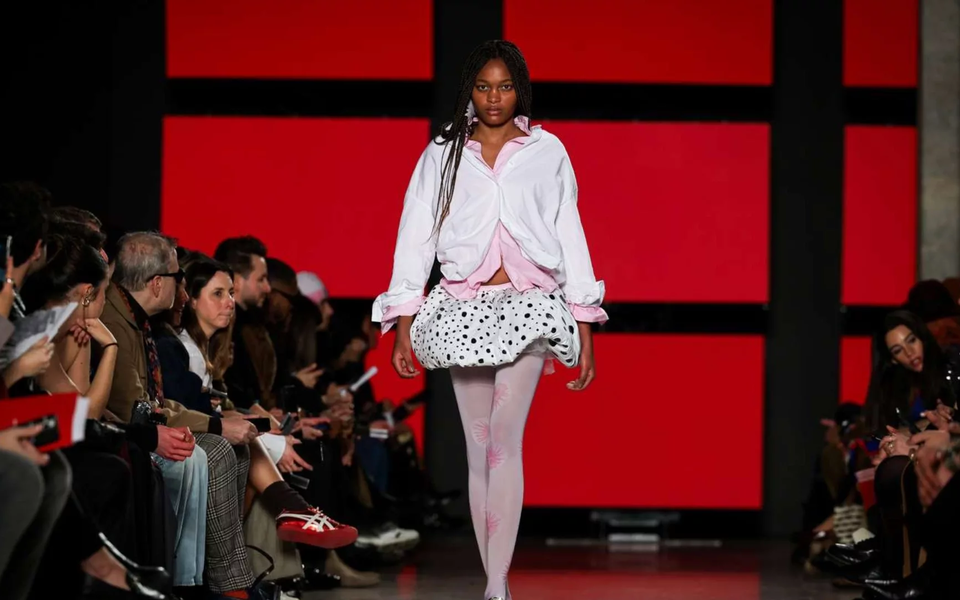 Female model walking the runway in a polka dot skirt, oversized shirt and tights, during a fashion show in Lisbon
