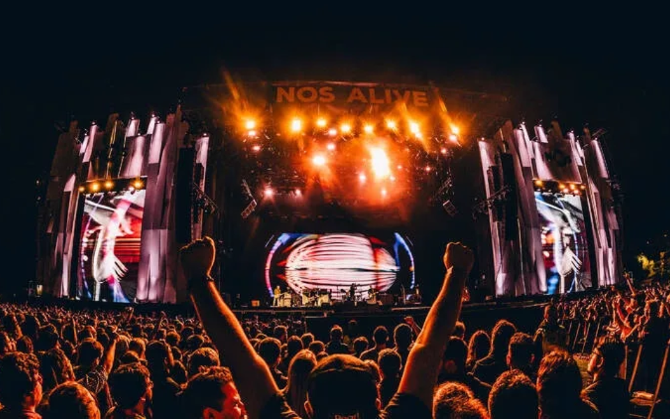 Crowd cheering at the brightly lit NOS Alive main stage at night
