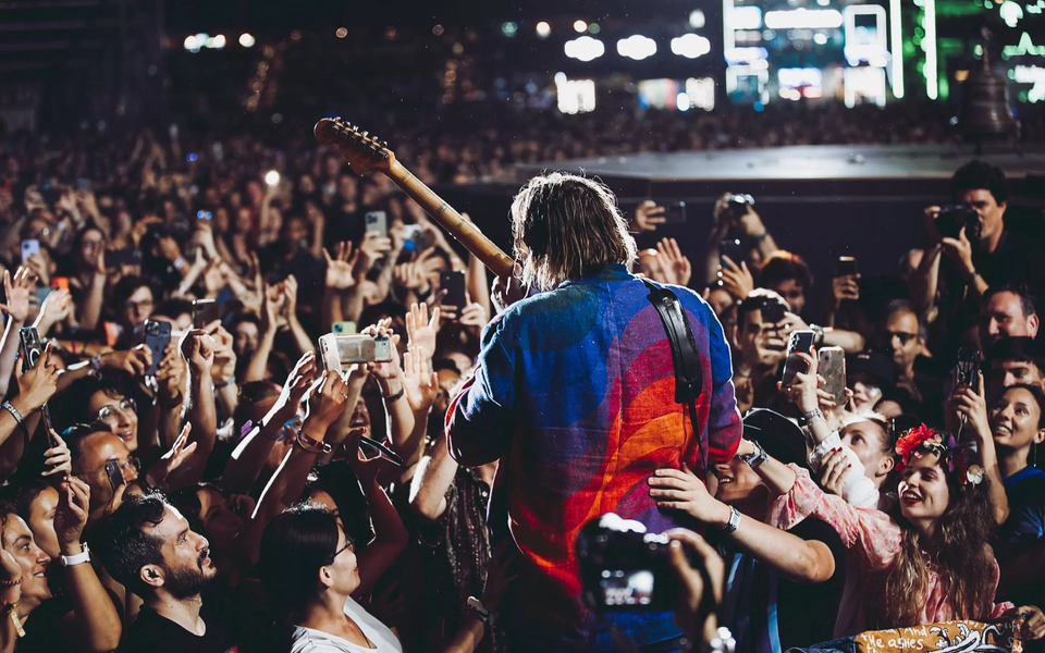 Crowd cheering and taking photos of a musician during a live performance at NOS Alive music festival in Lisbon, Portugal.