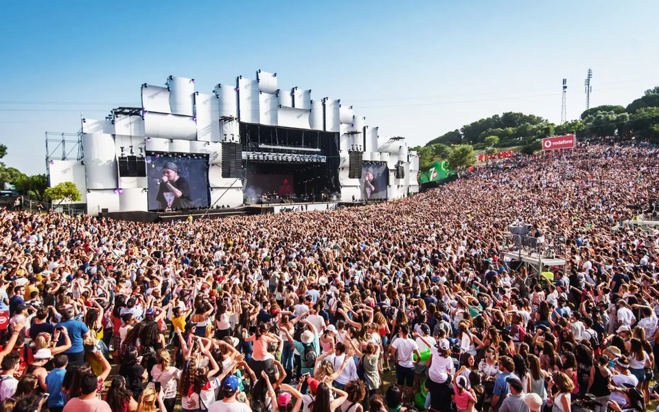 Thousands of people enjoying a daytime concert at Rock in Rio Lisboa with the main stage and large video screens in the background