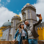 A happy couple takes a selfie in front of the stunning Pena Palace in Sintra, Portugal, capturing a beautiful moment together.