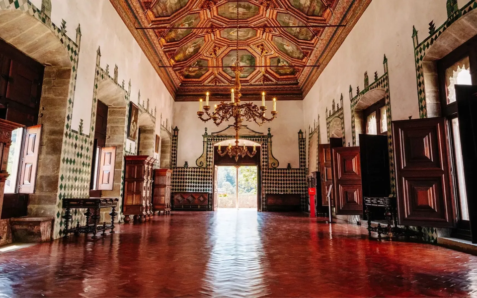 Ornate hall with wooden ceiling, tiled walls, and antique furniture inside the National Palace of Sintra.
