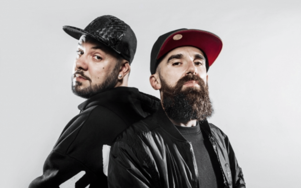 Portrait of rappers performing at the Throwback 00s Hip Hop & RnB event in Lisbon. They are dressed in streetwear and posed back-to-back, representing urban culture and nostalgia from the 2000s music scene.