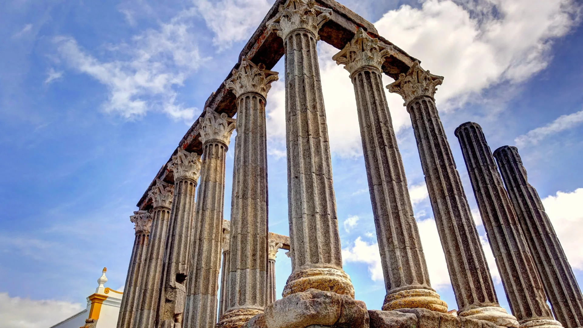 Close-up view of the Roman Temple of Évora, also known as the Temple of Diana, with its tall Corinthian columns against a blue sky.
