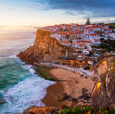 View of Azenhas do Mar village in Portugal at sunset, with its natural ocean pool and houses perched on the cliff.