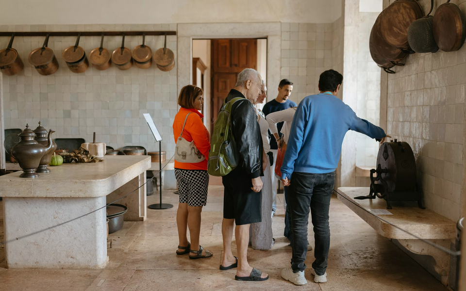 Group visiting the historic kitchen of Mafra National Palace with copper utensils on display