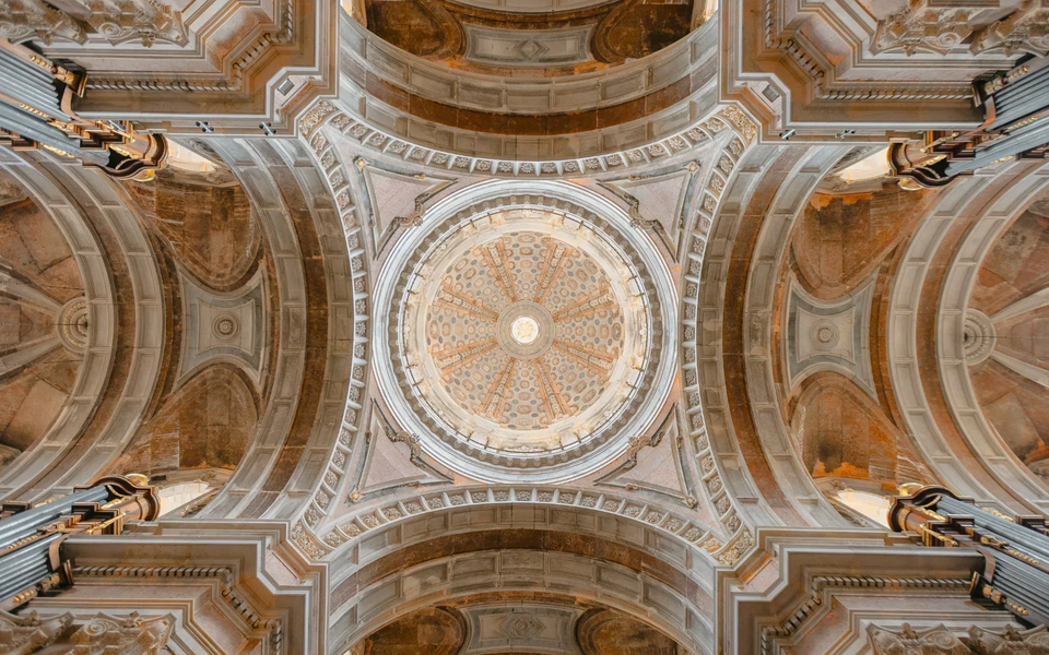 Intricate view of the central dome of Mafra National Palace's Basilica, showcasing Baroque symmetry, stone carvings, and organ pipes in Portugal.