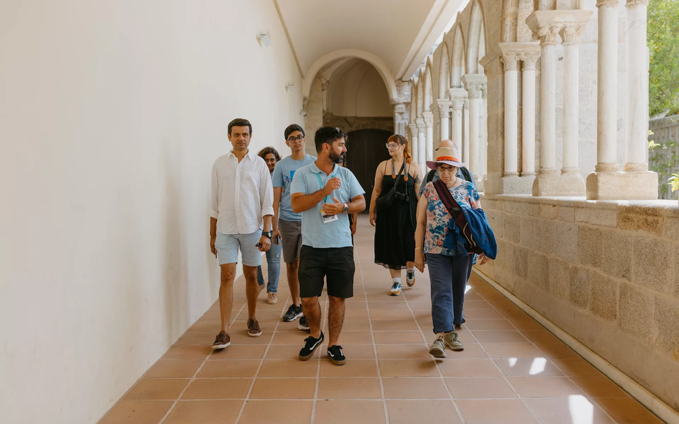 Tourists stroll down a hallway, enjoying an Évora guided tour, surrounded by beautiful architecture and history.