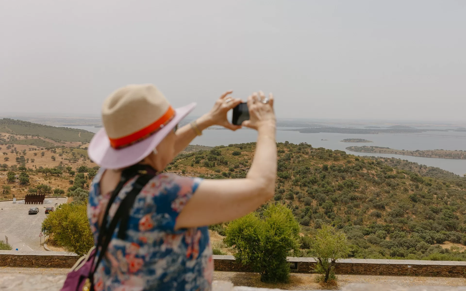 A tourist in Monsaraz captures a stunning photo of a serene lake surrounded by majestic mountains.